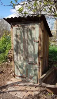 picture of the front of an old shed with a sloping tin roof a green door